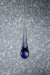 Gota de vidro azul semi transparente em fundo cinza com brilhantes. Fotografia em close up de uma...