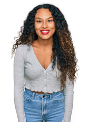 Young hispanic woman with curly hair wearing casual clothes with a happy and cool smile on face....