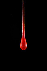 Gota de vidro vermelho semi transparente em fundo preto. Fotografia em close up de uma peça...