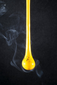Naklejki Gota de vidro amarelo semi transparente em fundo preto. Fotografia em close up de uma peça similar a um líquido de alta viscosidade pingando com fundo de efeito especial de cenário neutro.
