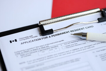 Application for permanent resident card on table with pen close up