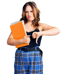 Young beautiful caucasian woman holding book with angry face, negative sign showing dislike with...
