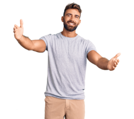 Young hispanic man wearing casual clothes looking at the camera smiling with open arms for hug. cheerful expression embracing happiness.