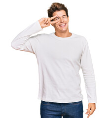 Handsome caucasian man wearing casual white sweater doing peace symbol with fingers over face, smiling cheerful showing victory