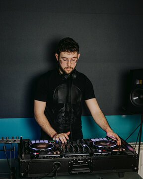 Concentrated DJ mixing tracks at a club setup