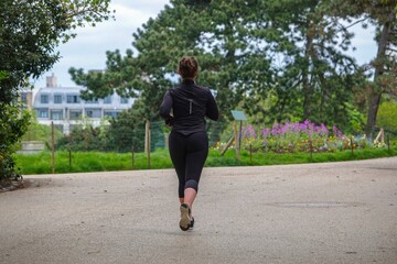 Une femme faisant son footing dans un parc - obrazy, fototapety, plakaty