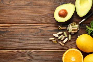Different vitamin pills and fresh fruits on wooden table, flat lay. Space for text