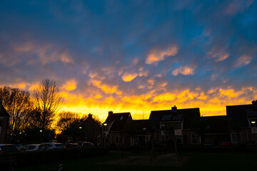 Houses are silhouetted against a colourful display of mammatus clouds at sunset