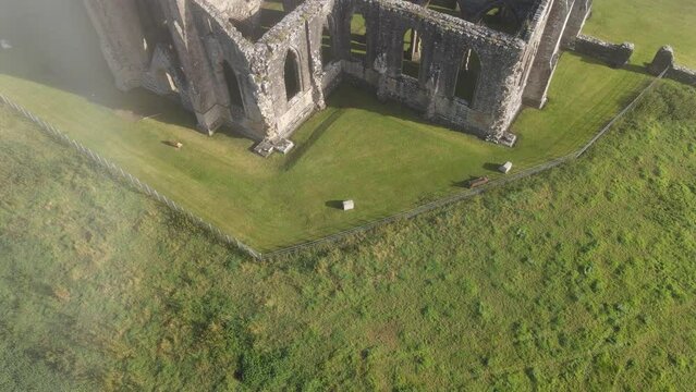 Drone shot of the ruins of Tintern Abbey on a foggy morning in Tintern village, Wales, UK