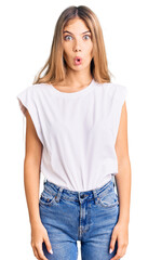 Fototapeta premium Beautiful caucasian woman with blonde hair wearing casual white tshirt afraid and shocked with surprise expression, fear and excited face.