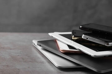 Many different modern gadgets on grey table, closeup. Space for text