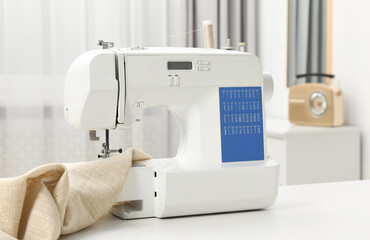 Sewing machine and fabric on white table in workshop