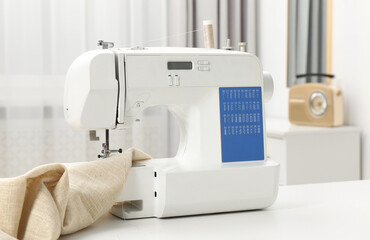 Sewing machine and fabric on white table in workshop