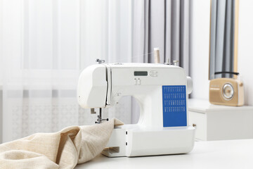 Sewing machine and fabric on white table in workshop