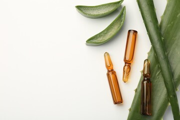 Skincare ampoules and aloe leaves on white background, flat lay. Space for text