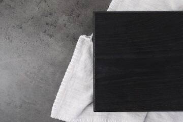 Wooden cutting board and napkin on grey table, top view. Space for text