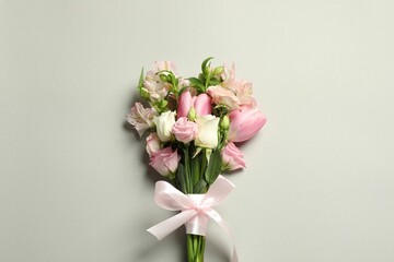 Happy Mother's Day. Bouquet of beautiful flowers tied with pink ribbon on light grey background, top view