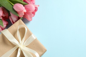 Happy Mother's Day. Beautiful pink tulips and gift box on light blue background, flat lay. Space for text