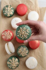 Woman with decorated Christmas macaron at table, top view