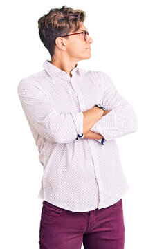 Young handsome man wearing business clothes and glasses looking to the side with arms crossed convinced and confident