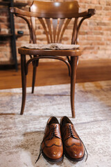 Stylish retro brown shoes on the floor. Classic men's shoes. Background of chair and brick wall. Place for text