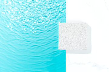 Minimal cosmetics product presentation mockup scene made with porous stone near the blue water. Flat lay background with copy space. Ideal for personal care cosmetics or sun creams.