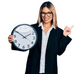 Young hispanic woman holding big clock smiling happy pointing with hand and finger to the side