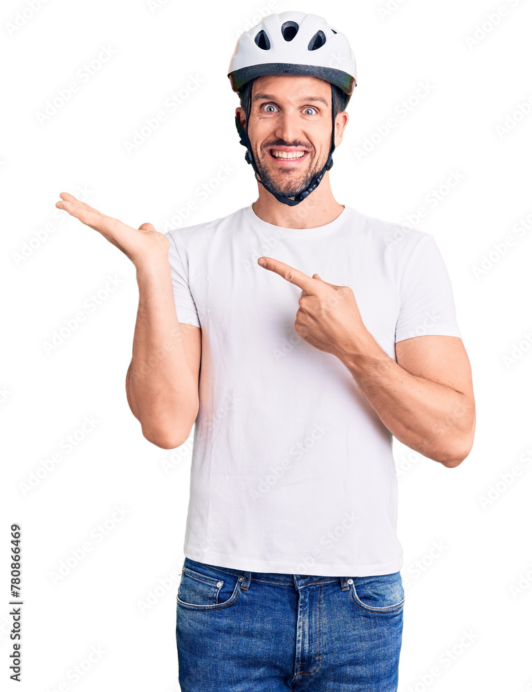 Poster young handsome man wearing bike helmet amazed and smiling to the camera while presenting with hand a