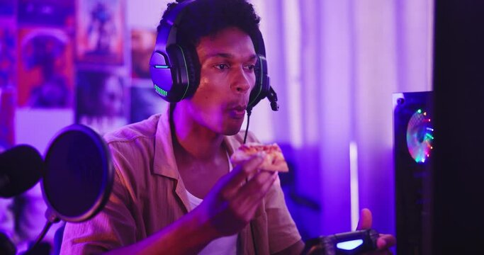 Man, streamer or gamer eating in home for online battle, challenge or esports contest to relax. Night, break or gaming pro with food, meal or pizza for content creation, podcast or social media chat