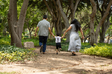 Fototapeta premium family walking in the park holding hands happily