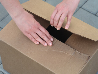 A woman opening a cardboard box. Close up.