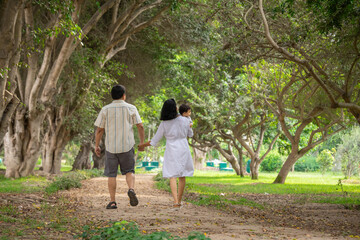 Obraz premium Family holding hands together and walking quietly on a park during a sunny day