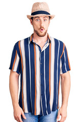 Young handsome caucasian man wearing summer hat afraid and shocked with surprise expression, fear and excited face.