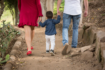 Family holding hands together and walking quietly on a park during a sunny day