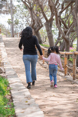Fototapeta premium Family holding hands together and walking quietly on a park during a sunny day