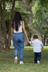 Obraz premium Family holding hands together and walking quietly on a park during a sunny day