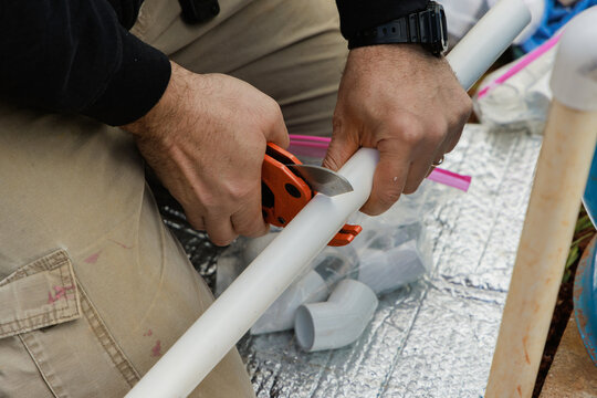 Plumber uses special scissors to cut plastic PVC pipe