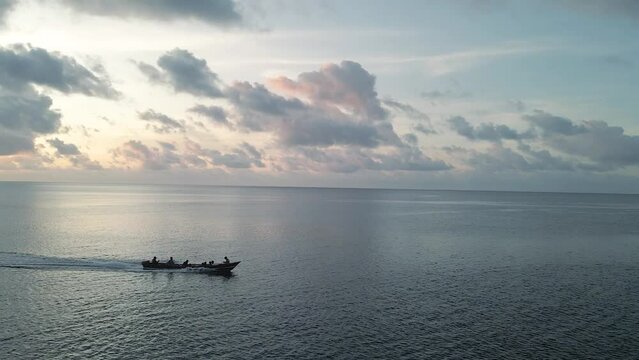 Aerial tracking of a wooden boat in the bay of Banda Neira during sunset. 