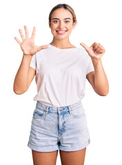 Young beautiful blonde woman wearing casual white tshirt showing and pointing up with fingers number six while smiling confident and happy.