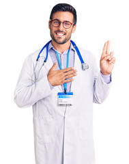 Young hispanic man wearing doctor uniform and stethoscope smiling swearing with hand on chest and fingers up, making a loyalty promise oath