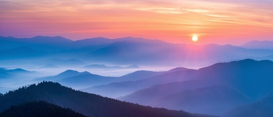 Fototapeta premium Sunrise over mountains with rays piercing through mist and trees. Warm, tranquil landscape.