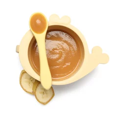 Schilderijen op glas Delicious baby food in bowl, spoon and cut banana isolated on white, top view © New Africa