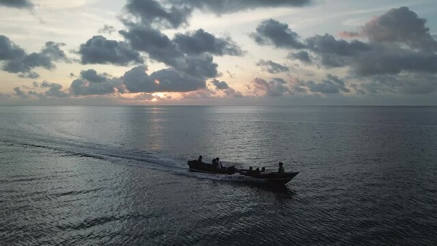 Aerial tracking of a wooden boat in the bay of Banda Neira during sunset. 