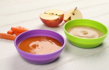 Baby food. Purees of apples and carrots in bowls on white wooden table