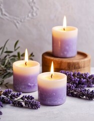 Obraz na płótnie Canvas Three burning wax candles and lavender flowers on a light background. Cozy home comfort, relaxation and wellness concept for a banner, flyer, poster or postcard with copy space.