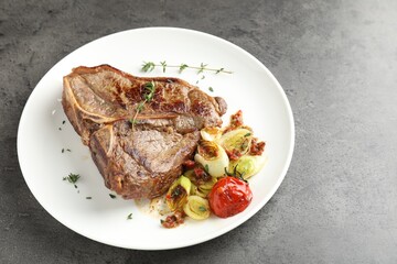 Delicious fried beef meat and vegetables on grey table