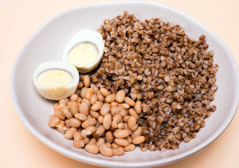 Top view, boiled buckwheat in a plate with a boiled egg, healthy food boiled beans, porridge in a plate. Fitness food for weight loss. Protein with yolk.