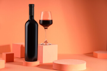 Stylish presentation of delicious red wine in bottle and glass on orange background. Space for text