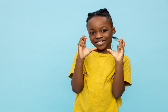 Hopeful African American little boy standing with crossed fingers