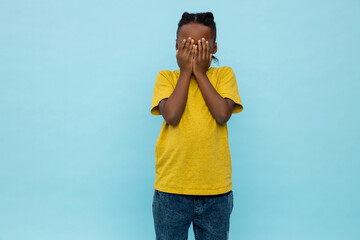 Scared dark- skinned little boy covering his eyes